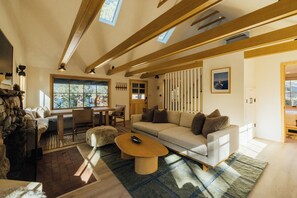 A modern living room with a sofa, coffee table, and a fireplace. - Aurora Hygge - Lakefront Luxury Home with Sauna, Hot Tub, Lake Views (Big Bear Lake)
