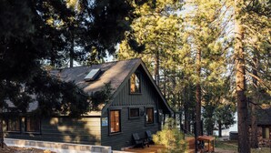 A cabin with a sloped roof, large windows, and a porch with seating. - Aurora Hygge - Lakefront Luxury Home with Sauna, Hot Tub, Lake Views (Big Bear Lake)
