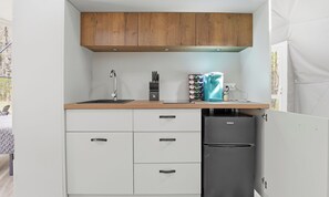 Een kleine keuken met een spoelbak, een koffiezetapparaat en een koelkast.