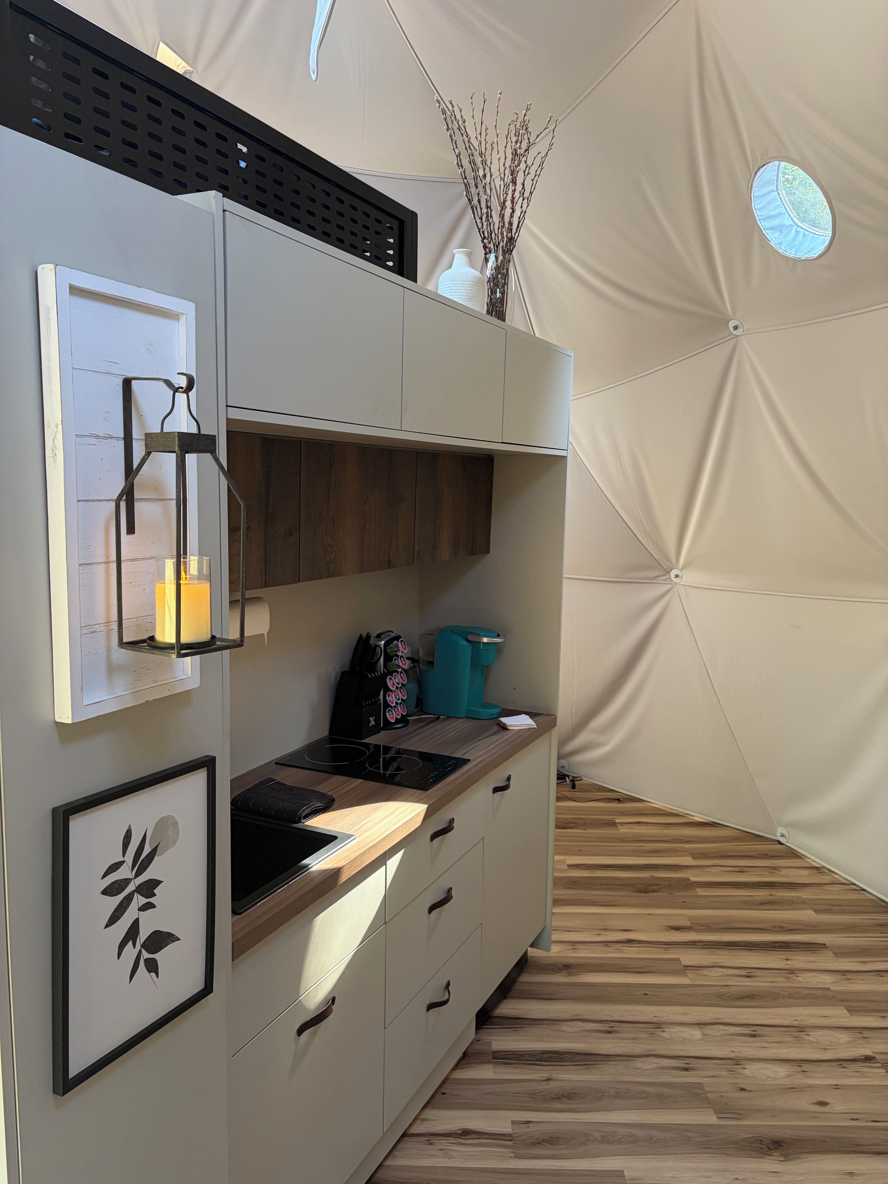 A modern kitchen with a built-in stove, a coffee maker, and a cabinet with a decorative vase.