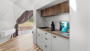 Una cocina con carpa, que incluye un lavamanos, armarios y una cafetera.