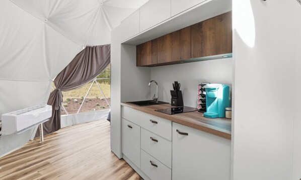 A tented kitchen with a sink, cabinets, and a coffee maker.