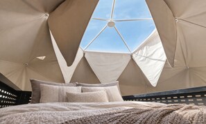 Un lit donnant sur le ciel, grâce à une structure de fenêtre aux motifs géométriques.