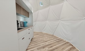 Une cuisine moderne dotée d’un plan de travail en bois, de meubles blancs et d’un motif géométrique original sur le mur.