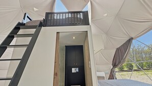 Alojamiento en tienda de campaña con una escalera que lleva a una puerta, un ventanal pequeño y vistas del exterior.