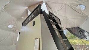 Una tienda de campaña con un poste central, un ventanal pequeño y un letrero en la pared.
