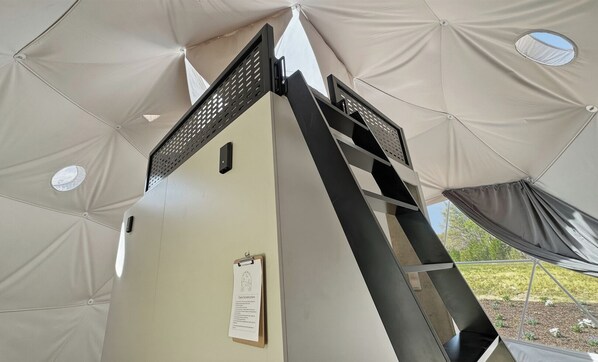 Een tent met een centrale paal, een klein raam en een bord aan de muur.