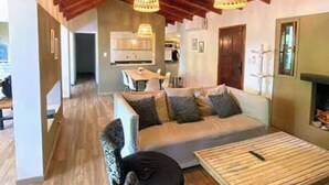 Un amplio salón con techo de madera, un conjunto de sofás, una mesa de centro y una chimenea.
