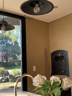 A room with a large window, a black heater, and a white flower vase.