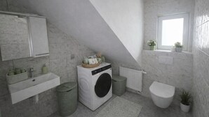 Moderni kylpyhuone, jossa on sisäänrakennettu pesukone, pesuallas ja wc.