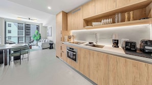 Una cocina moderna con armarios de madera, horno empotrado, cafetera y pileta.