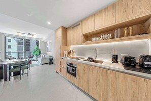 A modern kitchen with wooden cabinets, a built-in oven, a coffee machine, and a sink. - Spacious 1BR | Steps to Kaseya Center (Miami)
