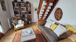 Ein gemütliches Wohnzimmer mit Bücherregal, Sofa, Sessel und Tisch.