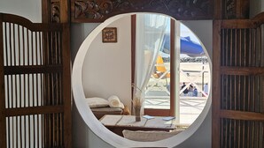 Ein rundes Fenster mit Blick auf einen Strand und ein Gebäude.