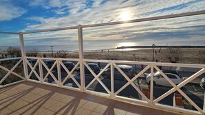 Ein Balkon mit Blick auf einen Strand und geparkte Autos.