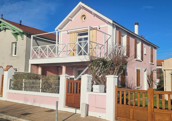 Een tweelaags huis met een balkon, een hek en een kleine tuin.