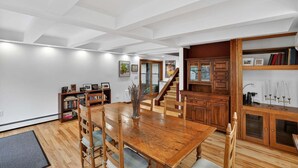A dining area with a wooden table and chairs, a bookshelf, and a staircase leading to another level. - Saratoga Cottage 2br Near Track & Lake 2 Bedroom Home (Saratoga Springs)