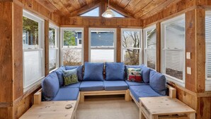 A cozy wooden room with a built-in sofa, a small table, and large windows. - Saratoga Cottage 2br Near Track & Lake 2 Bedroom Home (Saratoga Springs)