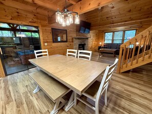 A wooden interior with a dining table, chairs, a fireplace, a TV, and a staircase. - Silver Maple Summit 2 Bedroom Cabin (Gatlinburg)