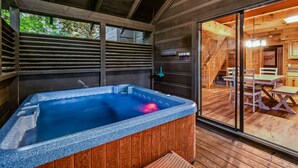 A wooden cabin with a hot tub, wooden deck, and a dining area with a table and chairs. - Silver Maple Summit 2 Bedroom Cabin (Gatlinburg)
