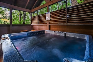 Ein Badebereich mit Thermalwasser, einem Holzdach und einem Schild mit Sicherheitsregeln.
