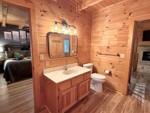 A wooden-paneled bathroom with a sink, toilet, and mirror. - Silver Maple Summit 2 Bedroom Cabin (Gatlinburg)