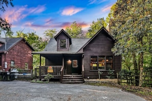 A two-story wooden cabin with a porch, surrounded by trees. - Silver Maple Summit 2 Bedroom Cabin (Gatlinburg)