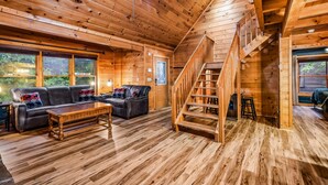 A wooden cabin interior with a sofa, coffee table, and a staircase. - Silver Maple Summit 2 Bedroom Cabin (Gatlinburg)
