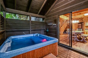 A wooden cabin with a hot tub, wooden deck, and a dining area with tables and chairs. - Silver Maple Summit 2 Bedroom Cabin (Gatlinburg)