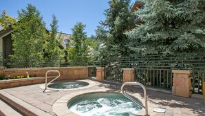 A pool area with two hot tubs, stone steps, and a metal fence. - Village Inn Plaza 218 2 Bedroom Condo (Vail)