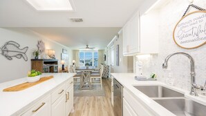 Eine moderne Küche mit weißen Schränken, einer Holz Arbeitsplatte und Blick zum Essbereich.