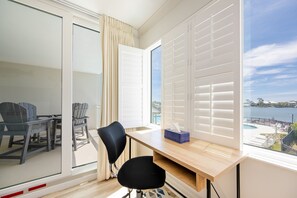 A room with a large window, a desk, two chairs, and a view of a body of water. - Back Bay 207 2 Bedroom Condo (Orange Beach)