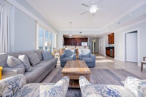 A spacious living room with a sofa, armchairs, a coffee table, and a view of the kitchen. - Phoenix Gulf Shores 1901 4 Bedroom Condo (Gulf Shores)