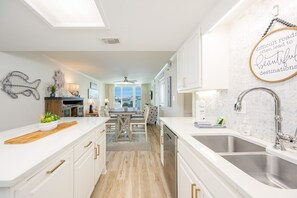 Eine moderne Küche mit weißen Schränken, einer Holz Arbeitsplatte und Blick zum Essbereich.