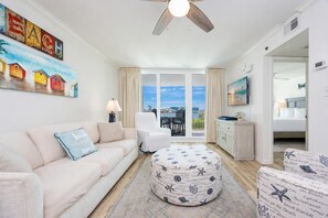 Ein Wohnzimmer mit Sofa, Hocker und Deckenventilator.