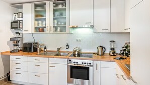 Eine moderne Küche mit weißen Schränken, Edelstahlgeräten und einer Holzausziehtafel.