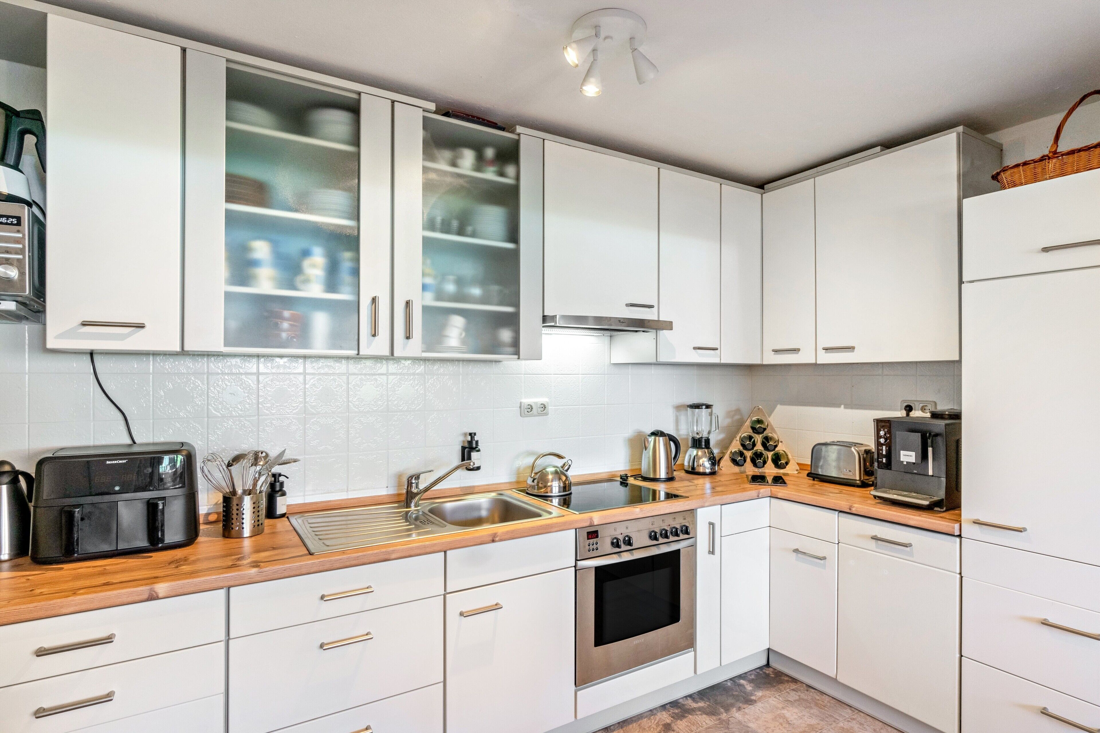 Eine moderne Küche mit weißen Schränken, Edelstahlgeräten und einer Holz Arbeitsplatte.