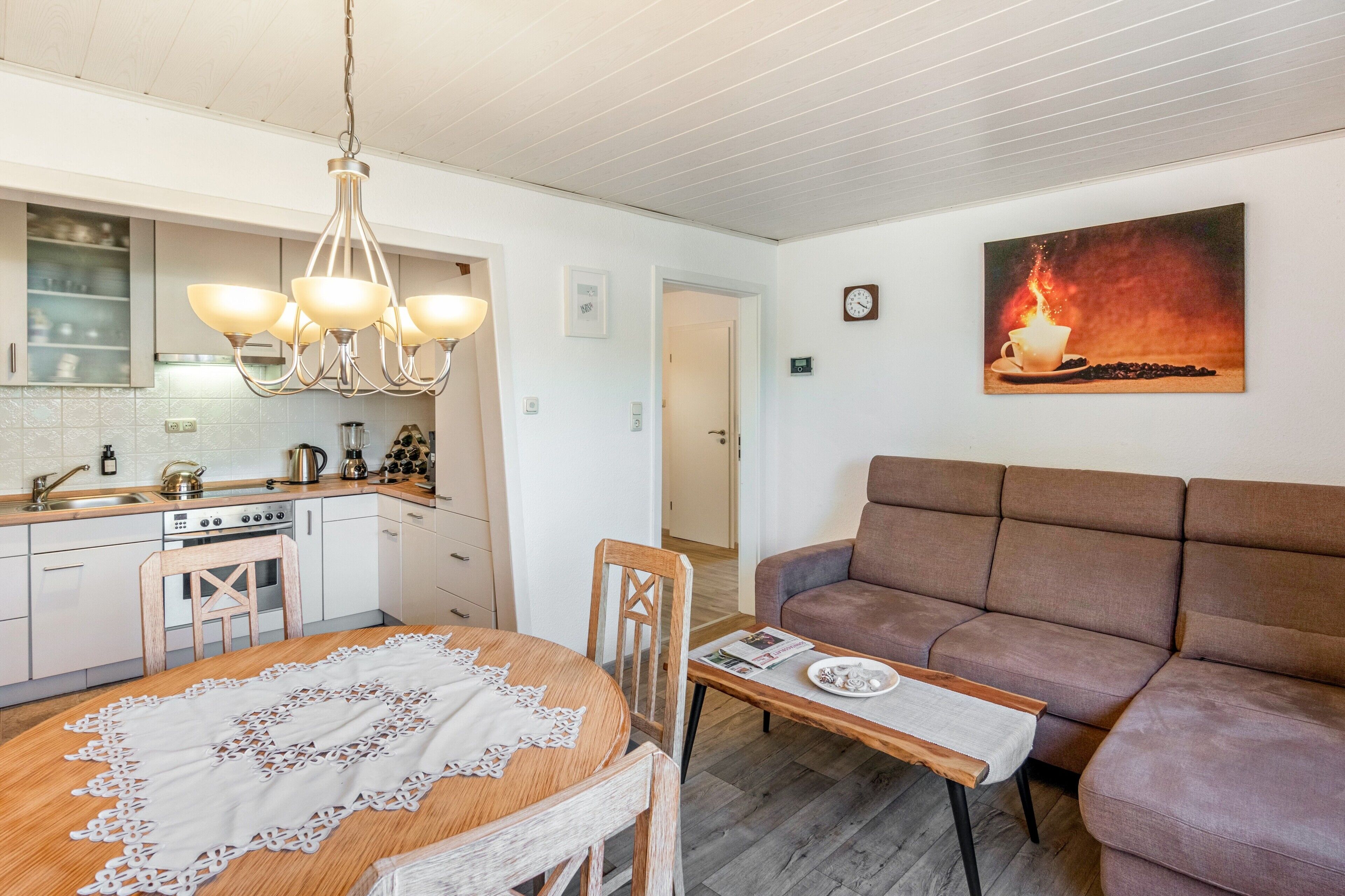 Une cuisine moderne avec un coin repas, un canapé et un tableau au mur.