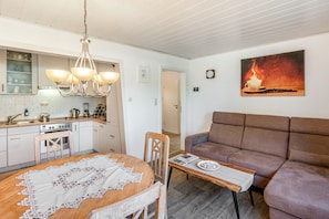 Et moderne køkken med spiseplads, en sofa og et billede på væggen.