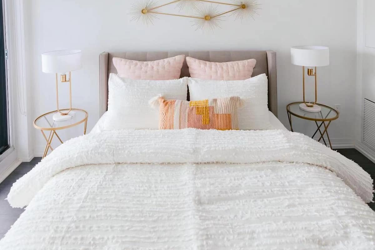 Een slaapkamer met een groot bed, twee nachtkastjes, een wandlamp en een raam.