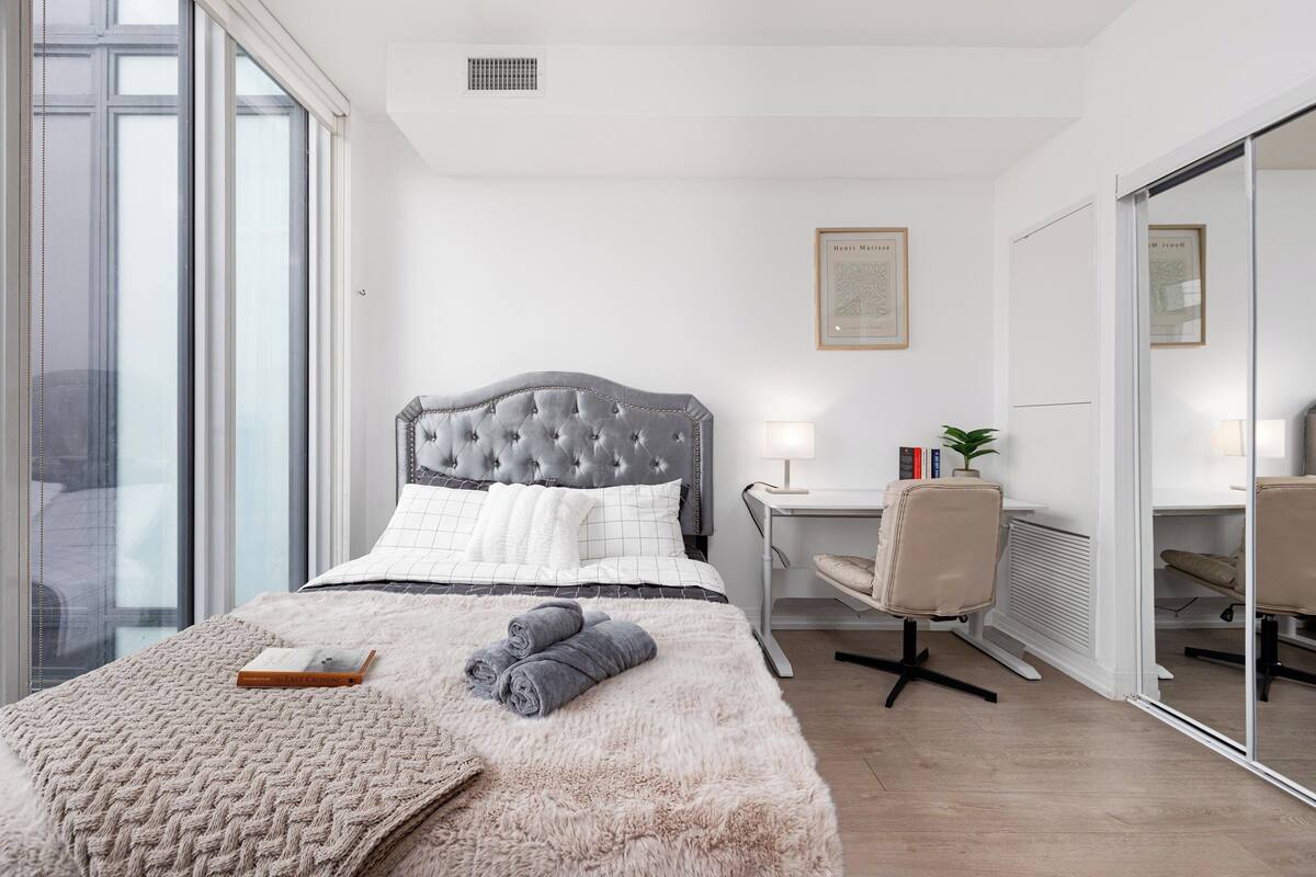 Een slaapkamer met een bed, een bureau, een stoel, een radiator en een raam.