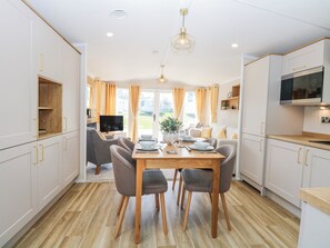 Een moderne keuken met witte kasten, een houten eettafel en een televisie.