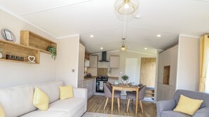 Un espacio habitable compacto con sofá, sillón, mesa de comedor y kitchenette.