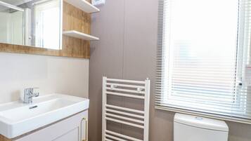 A bathroom with a white sink, mirror, and towel rack.