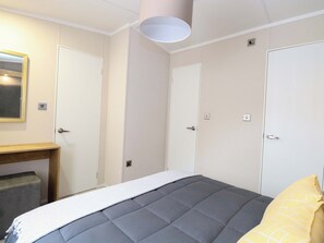 Un dormitorio con cama, mesita de noche, espejo y dos puertas.