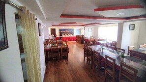 Un restaurante con mesas y sillas de madera, una zona de buffet y vistas a la montaña.