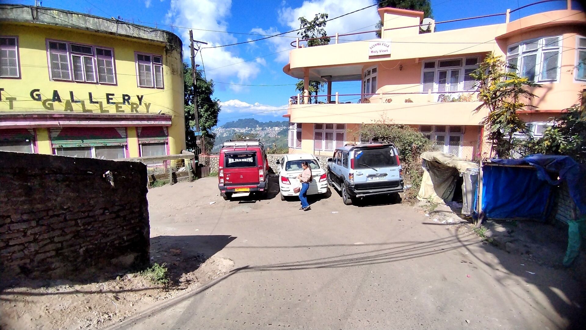 A street with parked cars, a building labeled 'T GALLERY,' and a sign for 'SUBHMA VILLAS.'