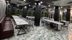 A conference room with marble flooring, dark wooden columns, and ceiling fans. - A ONE RESIDENCY (Gurugram)