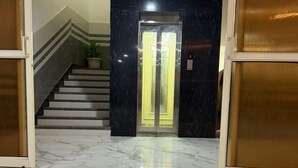 A marble-floored lobby with a staircase, a potted plant, and a double door elevator. - A ONE RESIDENCY (Gurugram)