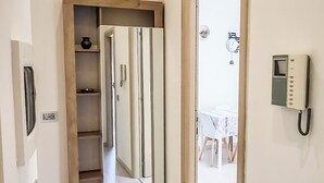 Ein Korridor mit einer Holztür, einem Telefon und einem Regal mit einer Vase.